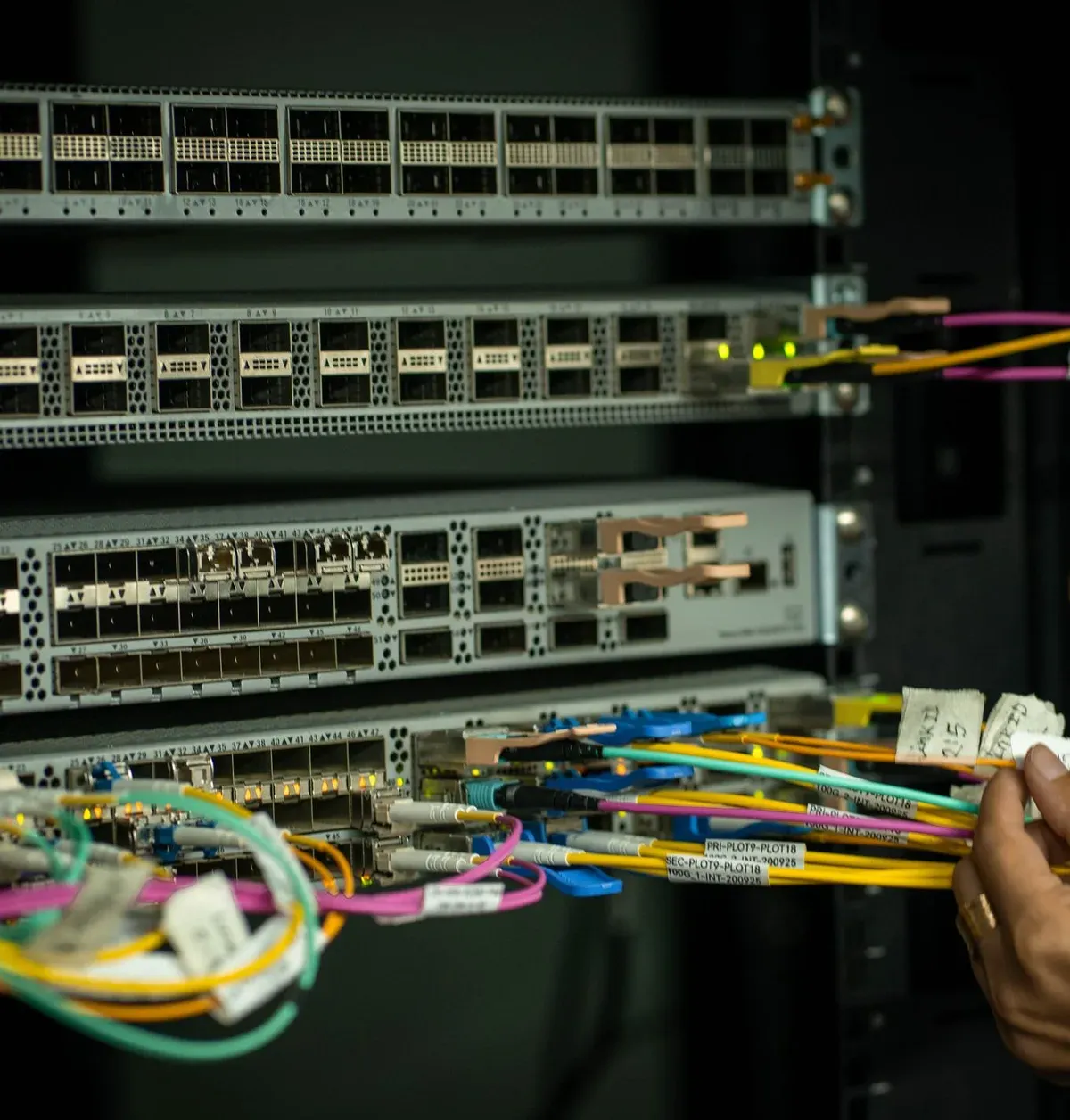 Hand plugging fibre cables in a server rack